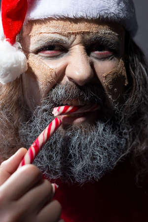 smiling santa with a grin, looking at the camera, evil santa dead - mummy. Christmas horror concept Santa Claus holding copyspace blank sign. Portrait Isolated on White Backgroundの写真素材