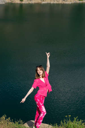 portrait of a fashionable beautiful young girl in pink, generation z. Against the background of the lake water.の写真素材