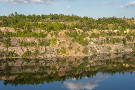 landscape of abandoned granite quarry in summer, in water reflection cloudy sky.の写真素材