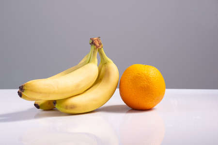 fruit minimalism bananas and orange on a white-gray background.の写真素材