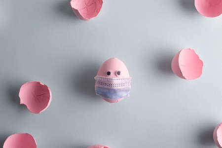 virus Easter egg in a protective mask concept painted in a pink-blue pastel shade eggshell....