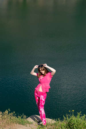 portrait of a fashionable beautiful young girl in pink, generation z. Against the background of the lake water.の写真素材