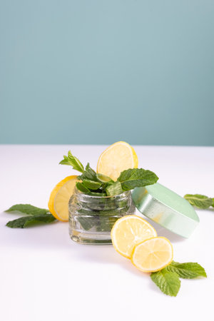 summer refreshing cosmetics with lemon and mint, ice cubes, in a glass container on a white background.の写真素材