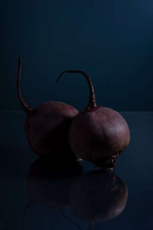 a pair of red beets on a black background minimalistic still lifeの写真素材