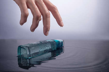 moisturizing the skin. hand takes a blue bottle with a liquid for moisturizing the skin of the face, on a white background. advertising photo of cosmetic products for skin care. In a humid environmentの写真素材