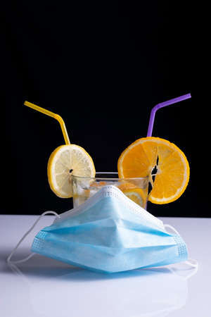 fruity cocktail in protective mask concept on white table and black backgroundの写真素材