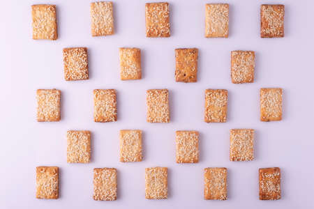 patterned mosaic of cookies with sesame seeds on a white background.の写真素材