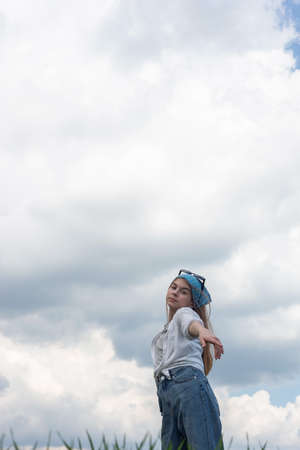 portrait of a little teenage girl in a bandana, against the backdrop of a cloudy sky.の写真素材