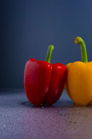 fresh yellow and red chili peppers blue background water drops on glass.の写真素材