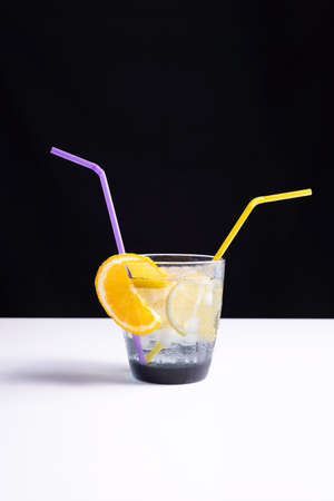 summer cocktail in a glass on a white table and black background. minimalistic concept.の写真素材