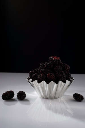 blackberries in a metal bowl, on a white background.