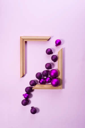 Christmas toys are poured into a wooden photo frame on a pink background. Christmas concept.
