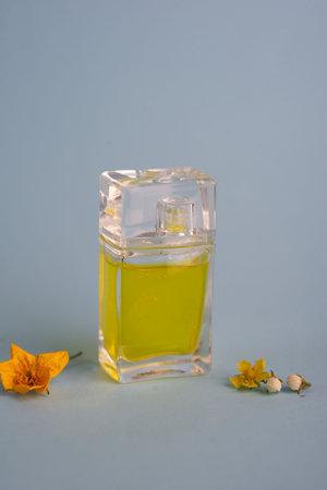 bottle of yellow perfume on a blue background flowers spring aroma.