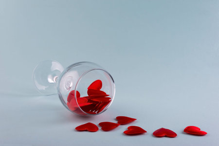 red hearts in a wine glass minimalism on a plain background.
