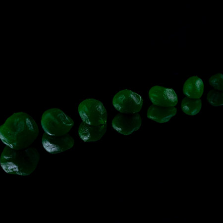 green dried fruits on black background.