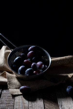 dramatic autumn still life with plums on a dark background. Rustic.の写真素材