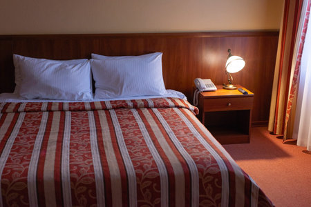 hotel bed interior with lamps in warm colors.の写真素材