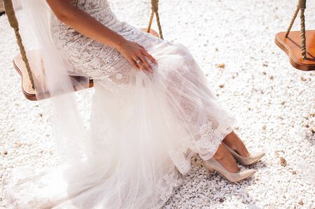 Gorgeous bride is sitting on a swing on a sunny dayの写真素材