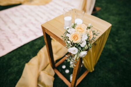 flowers and candles are standing on wooden boxe in wedding ceremony area decorated with fabricの写真素材