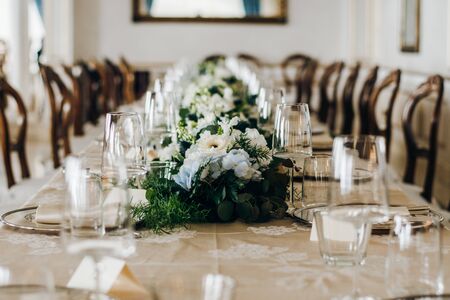 The wedding festive table is decorated with floral arrangements, glasses, plates and cutlery, the...