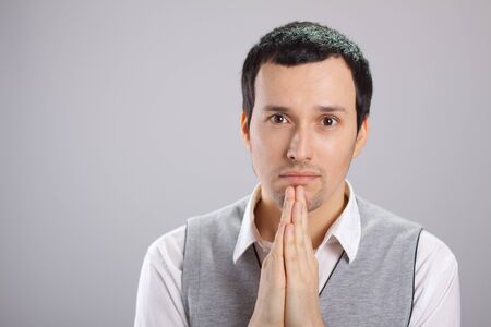 a young man with folded hands in the faceの写真素材