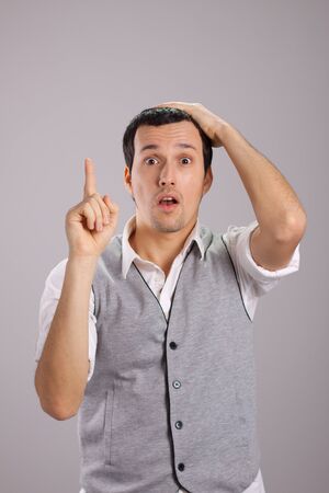 young guy with his hand on his head and a finger upの写真素材