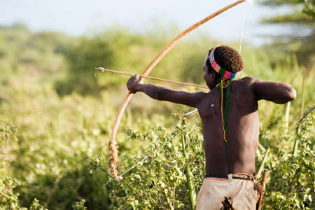 LAKE EYASI, TANZANIA - FEBRUARY 18  An unidentified Hazabe bushman with bow and arrow during hunting on February 18, 2013 in Tanzania  Hazabe tribe threatened by extinction のeditorial素材