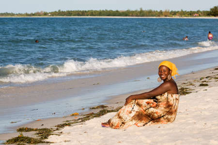 Beautiful happy african woman sitting on the beachの写真素材