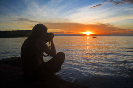 Silhouette of photographer taking photos at sunsetの写真素材