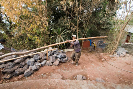 BARHIR DAR, ETHIOPIA - FEBRUARY 26, 2010: Unidentified Ethiopian worker carries heavy trunk to rebuild the monastery.のeditorial素材