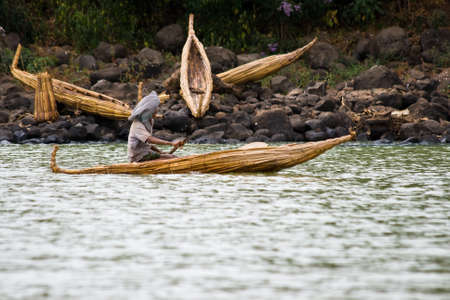 LAKE TANA, ETHIOPIA - FEBRUARY 26, 2010: Unidentified Ethiopian man transports goods in a papyrus boat on Lake Tana in Ethiopia.のeditorial素材