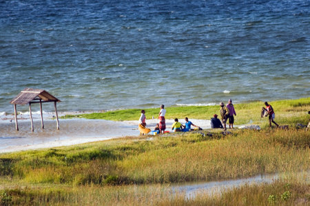 BILENE LAGOON, MOZAMBIQUE ? APRIL 08, 2015: Unidentified people sit and have a chat at the sandy beach of the Bilene lagoon.のeditorial素材