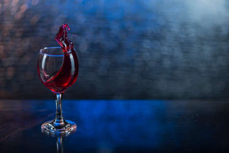 Splash in red juice or wine in a wineglass.の写真素材