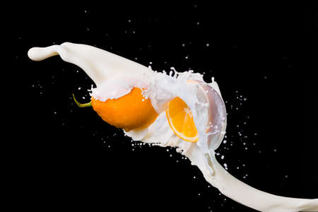two halves of lemon and splash of milk isolated on black background.の写真素材