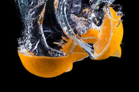 sliced orange underwater isolated on black background.の写真素材