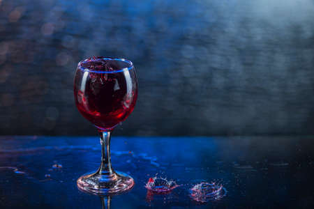 Splash in red juice or wine in a wineglass.の写真素材