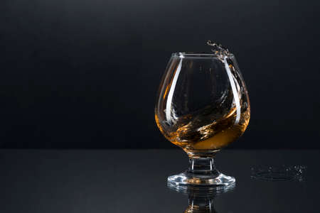 wineglass of cognac and splash on a gray gradient background.の写真素材