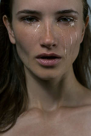 beauty portrait of the crying girl with tears on cheeks on a gray backgroundの写真素材