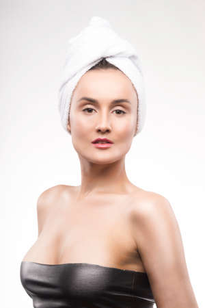 Portrait of the beautiful mature woman with a white towel on the head. Pure healthy skin. Spa, cosmetology, sauna.の写真素材