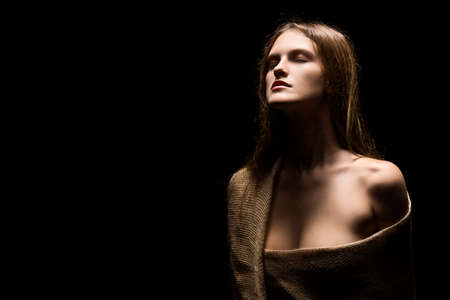 vintage portrait of naked big breast sensual girl covered with burlap fabric on a black background. big breast. deep decollete.  art photography. copy spaceの写真素材