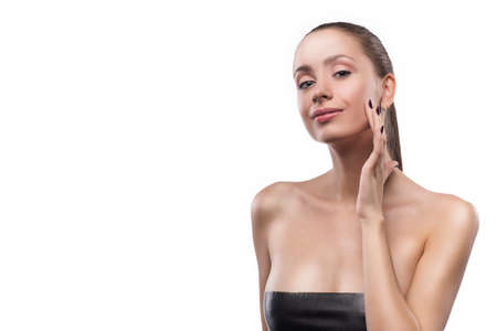 Portrait of beautiful young woman with clean, fresh skin touch her face on isolated white background. Cosmetology, beauty, spa. Copy spaceの写真素材