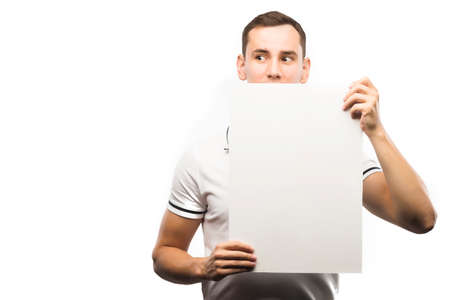 A young man holds an empty plate in his hands to fill your text. Emotional, courageous face. Isolated on white background. Copy space. Advertising, and commercial Design,の写真素材