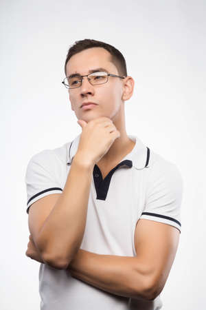 A young positive man in eyeglasses thinks. Emotional, courageous face. Isolated on white background....