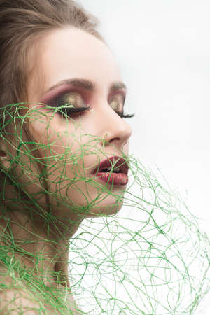 Beautiful naked shoulders young girl bride wearing green grass type veil mesh on her face. Isolated on white. Cosmetology, spa, skin care. Copy space. Advertising, conceptual and commercial designの写真素材