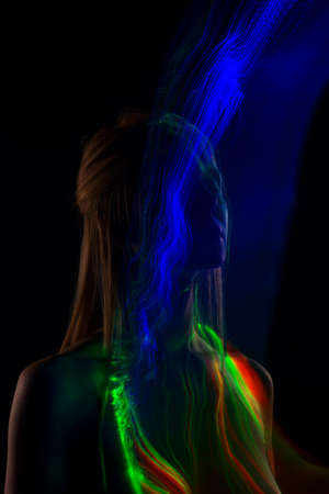 Conceptual avant-garde silhouette portrait of a beautiful blonde girl covered with multicolored lines applied by a lightbrush. Art photo.Copy space. Advertising, fashion and commercial Designの写真素材