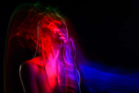 Conceptual avant-garde silhouette portrait of a beautiful blonde girl covered with multicolored lines applied by a lightbrush. Art photo.Copy space. Advertising, fashion and commercial Designの写真素材