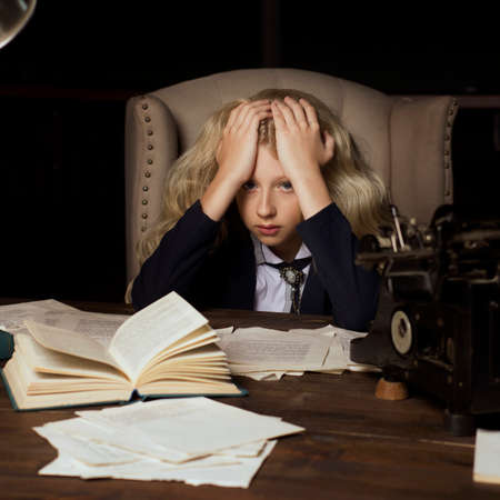 Beautiful long haired curly blonde schoolgirl tiredly learns homework in a classic vintage interior...