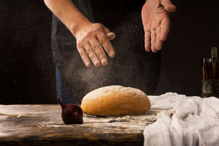 Conceptual art photography of a old woman hands drops hands, pour flour on bread. Copy space....