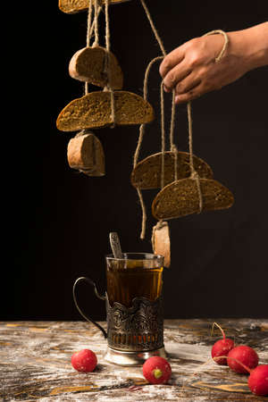 Conceptual art photography of a old woman hands holds pieces of bread hanging on ropes tied with...
