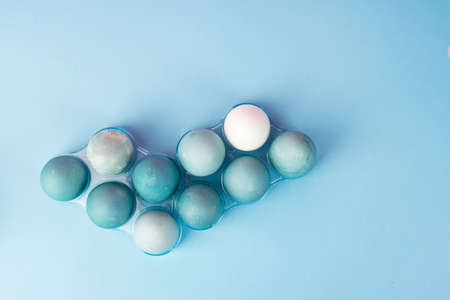 Conceptual still life photo of several blue eggs in plastic geometric egg boxes on the minimalist...